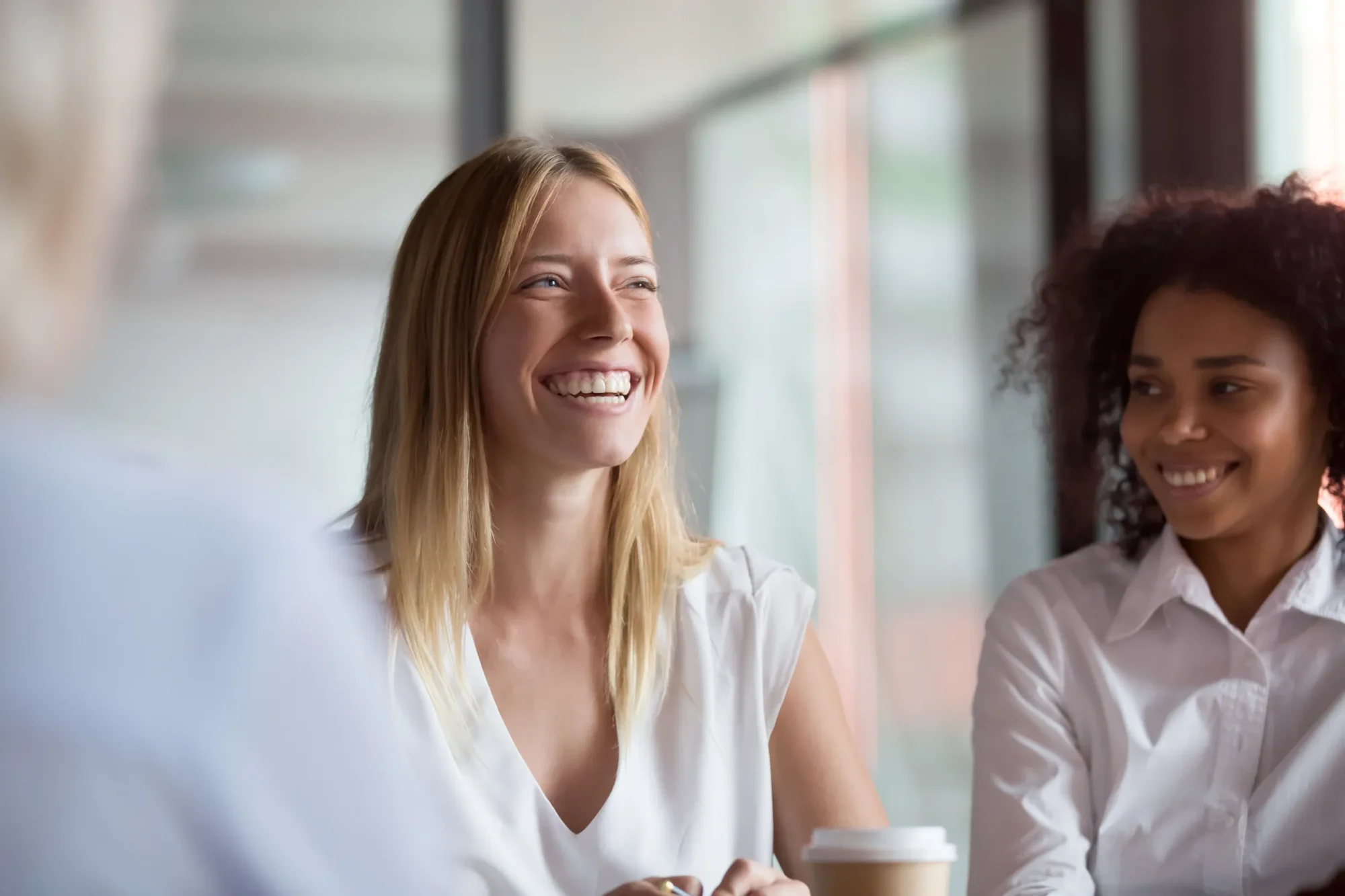 Smiling woman in a professional setting with colleagues.