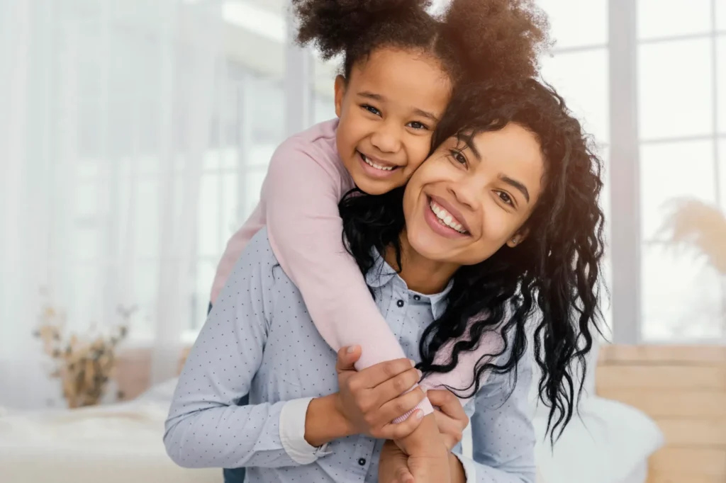 Mother playing at home with her young daughter, front view.
